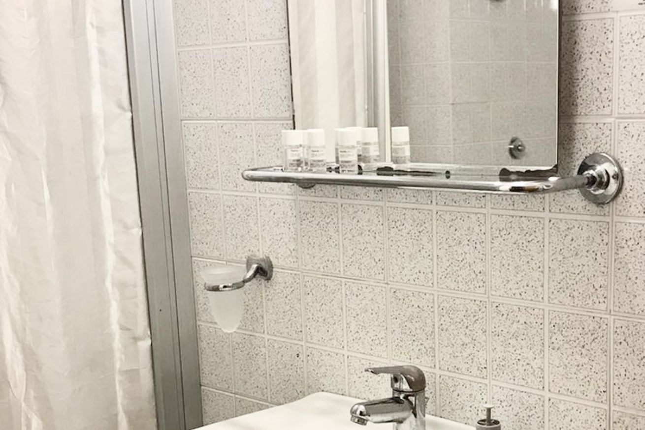 Une salle de bain équipée d’une douche, de toilettes, d’un lavabo et d’un miroir.