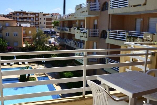 A balcony with a view of a swimming pool and adjacent buildings.