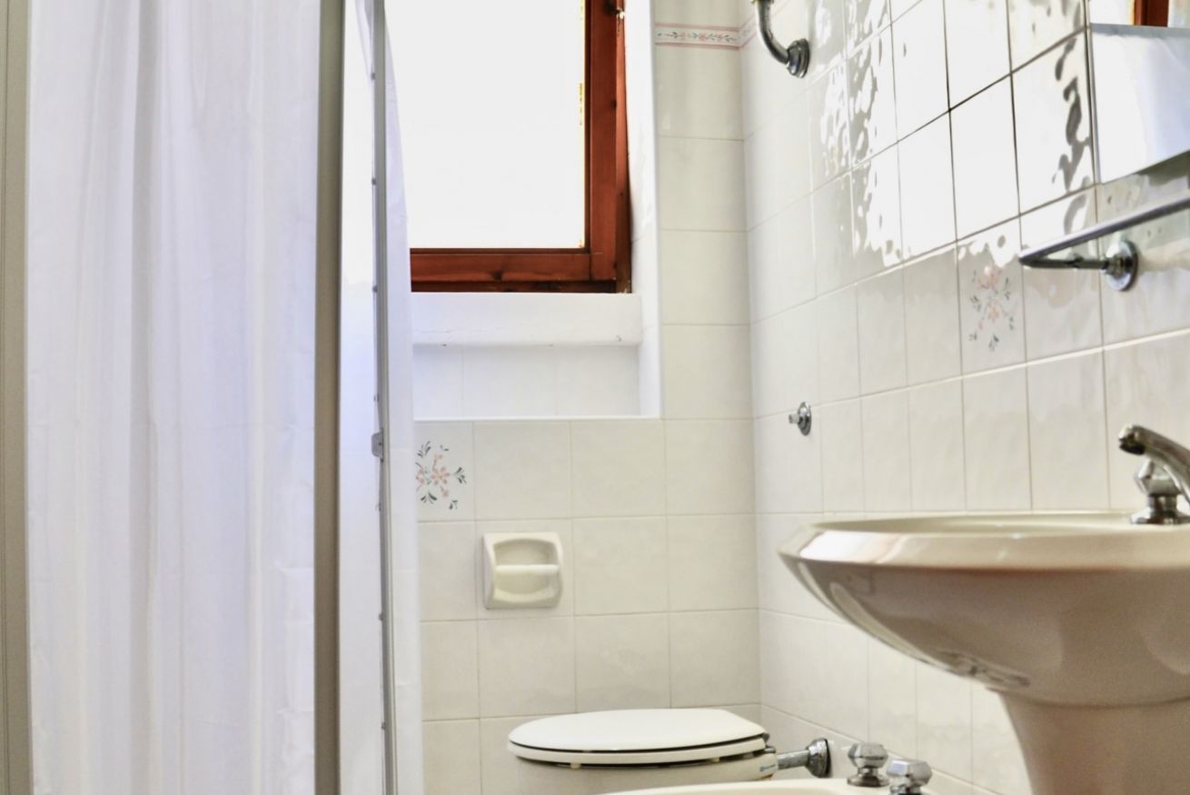 A small bathroom with a toilet, sink, and a window above the toilet.