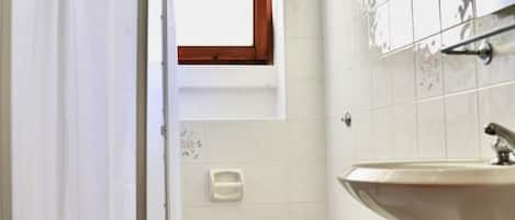A small bathroom with a toilet, sink, and a window above the toilet.