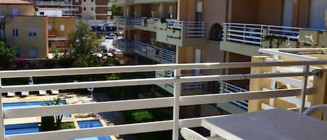 Ein Balkon mit Blick auf einen Swimmingpool und angrenzende Gebäude.