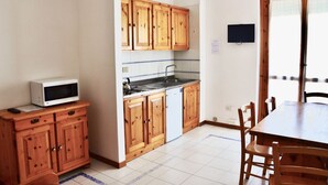 Une cuisine de taille réduite, dotée de meubles en bois, d’un four à micro-ondes et d’un évier.