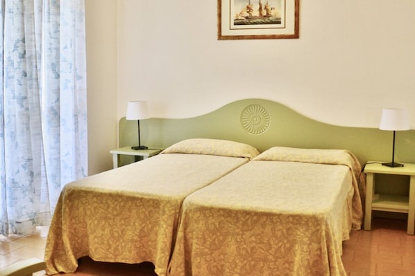 A double room with two beds, each with a matching nightstand and lamp.