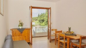 Una habitación con una mesa de comedor y sillas de madera, un banco y un pequeño armario con una planta.