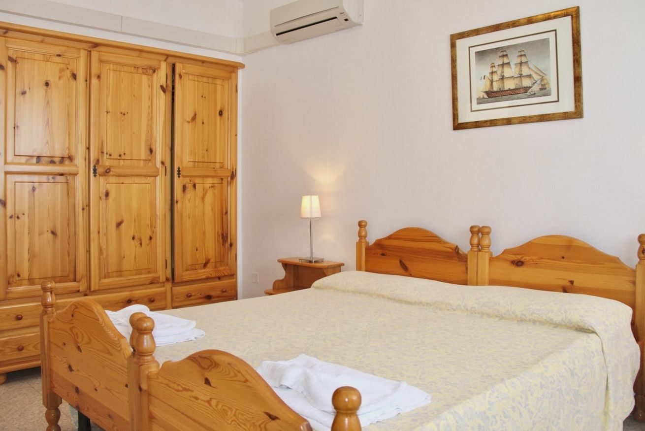 Ein Schlafzimmer mit Holzmöbeln, einem Bett, einem Nachttisch und einem Kleiderschrank.