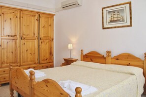 A bedroom with wooden furniture, a bed, a nightstand, and a wardrobe.