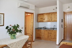 A compact kitchen with wooden cabinets, a granite countertop, and a dining area with a table and chairs.