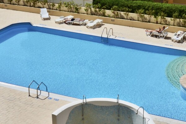 A swimming pool with lounge chairs and a sunbathing area.