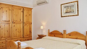 Une chambre à coucher avec des meubles en bois, un lit, une table de chevet et une armoire.