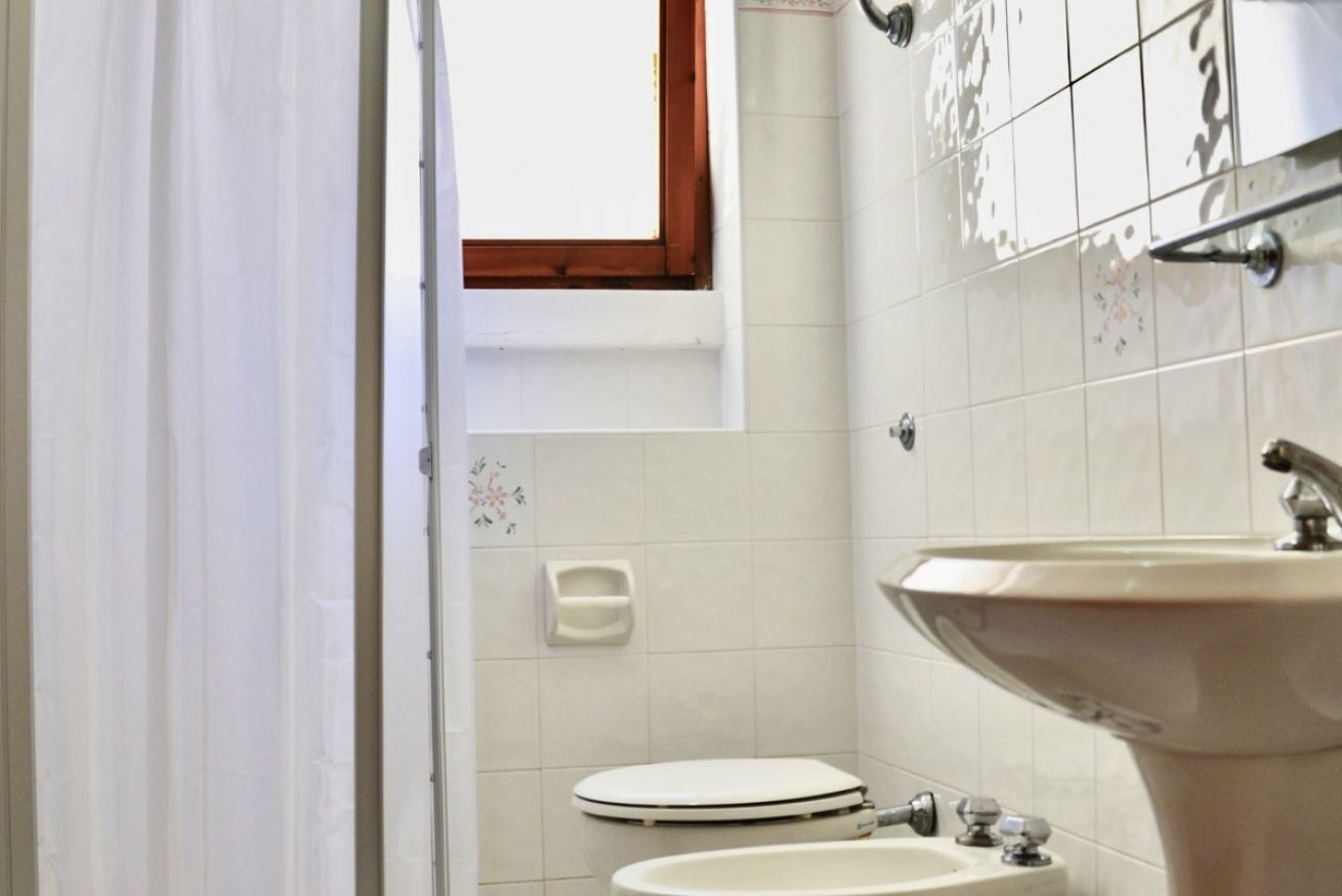 Ein Badezimmer mit Toilette, Waschbecken und einem Fenster über der Toilette.