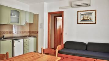 A compact living space with a kitchenette, a dining area, and a sofa.