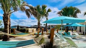 A beachside resort with hammocks, sun loungers, and umbrellas.
