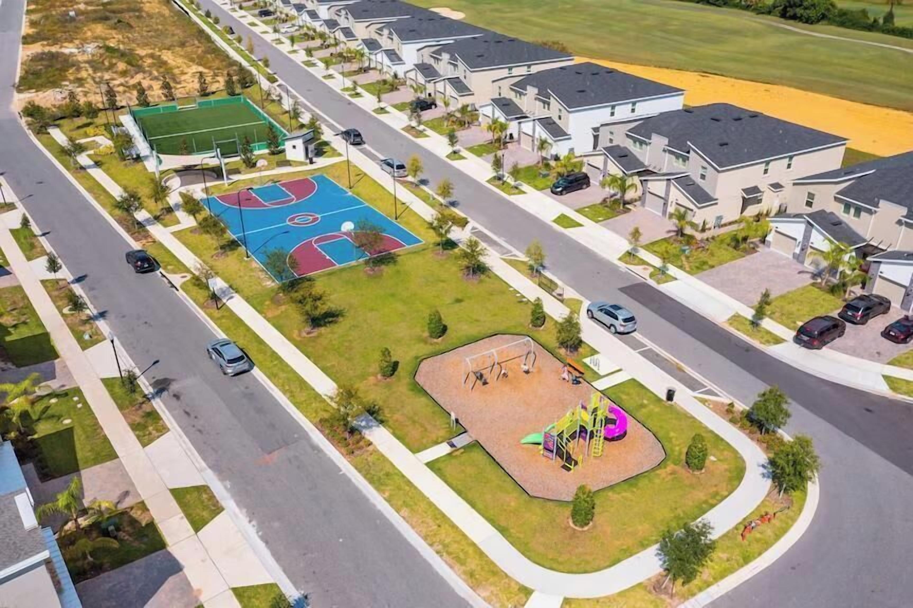 Ein Wohngebiet mit modernen Häusern, einem Basketballplatz und einem Spielplatz.