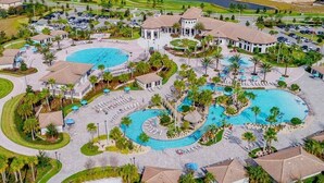 Luftaufnahme eines Resorts mit mehreren Schwimmbecken, Palmen und einem großen Gebäude mit Kuppeldach.
