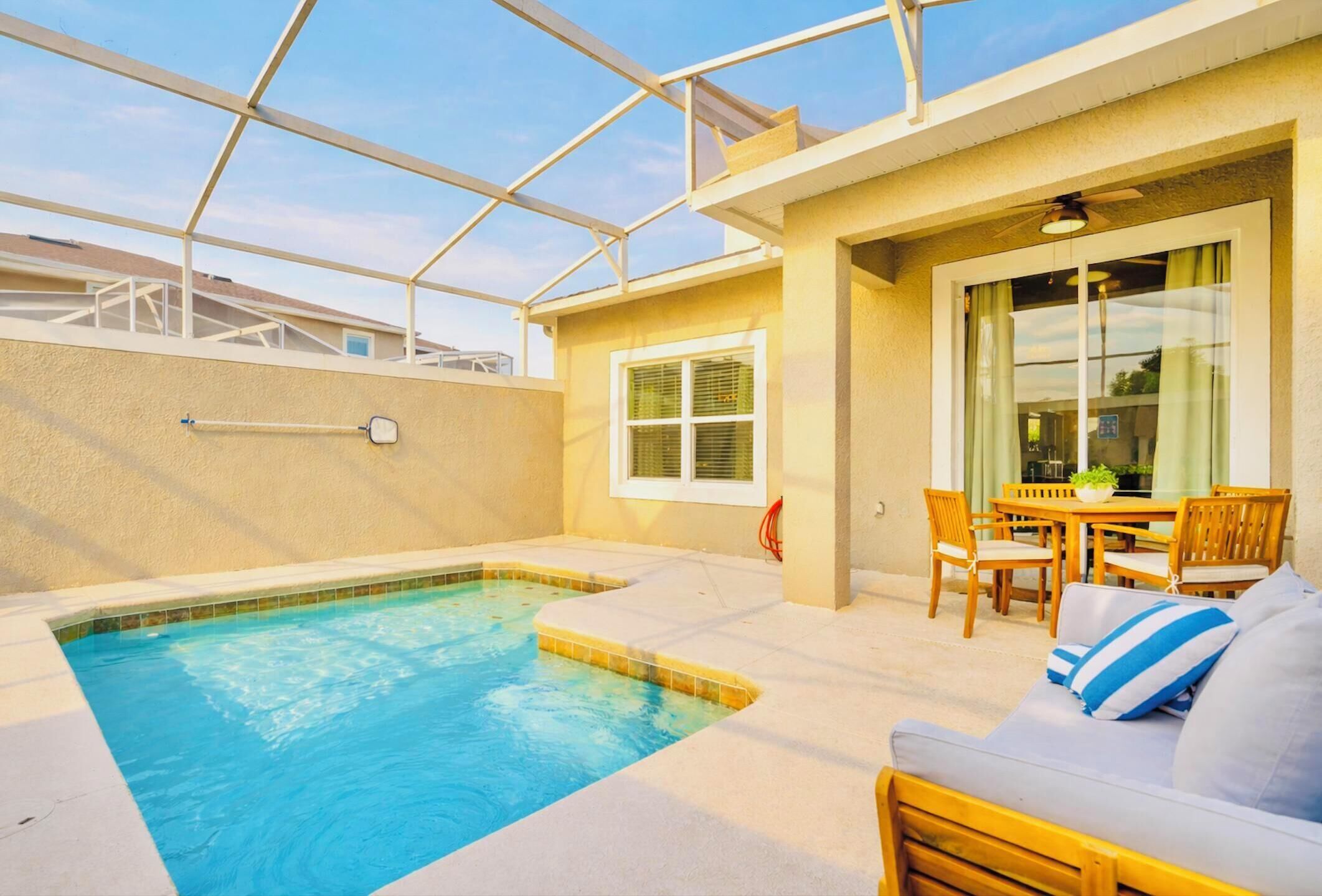 A rooftop pool area with a glass ceiling, a small pool, and a seating area with a table and chairs.