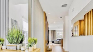 A modern hallway with a wooden floor, a built-in shelf with plants, and a large window at the end. - High-End 4BD in Luxury Reunion Resort 6mi Disney! (Kissimmee)