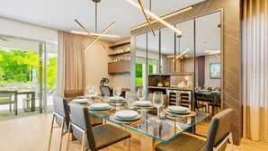 A modern dining area with a glass table, leather chairs, and contemporary lighting. - High-End 4BD in Luxury Reunion Resort 6mi Disney! (Kissimmee)