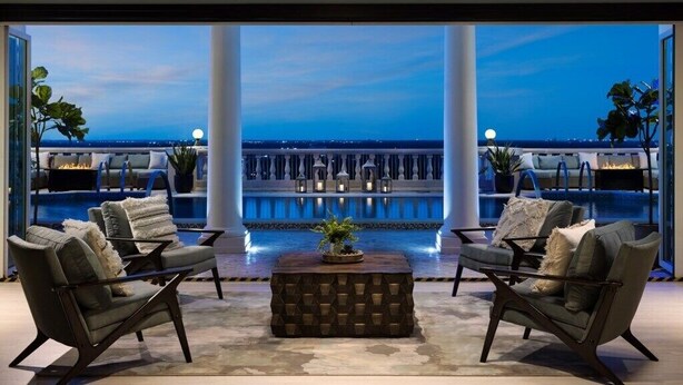 A rooftop lounge with two leather armchairs, a wooden coffee table, and a view of the sea at dusk. - High-End 4BD in Luxury Reunion Resort 6mi Disney! (Kissimmee)