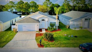 A residential neighborhood with single-family homes, a clear sky, and a well-maintained lawn. - Fantastic 5BD House w/Private Pool - 9mi/Disney! (Clermont)