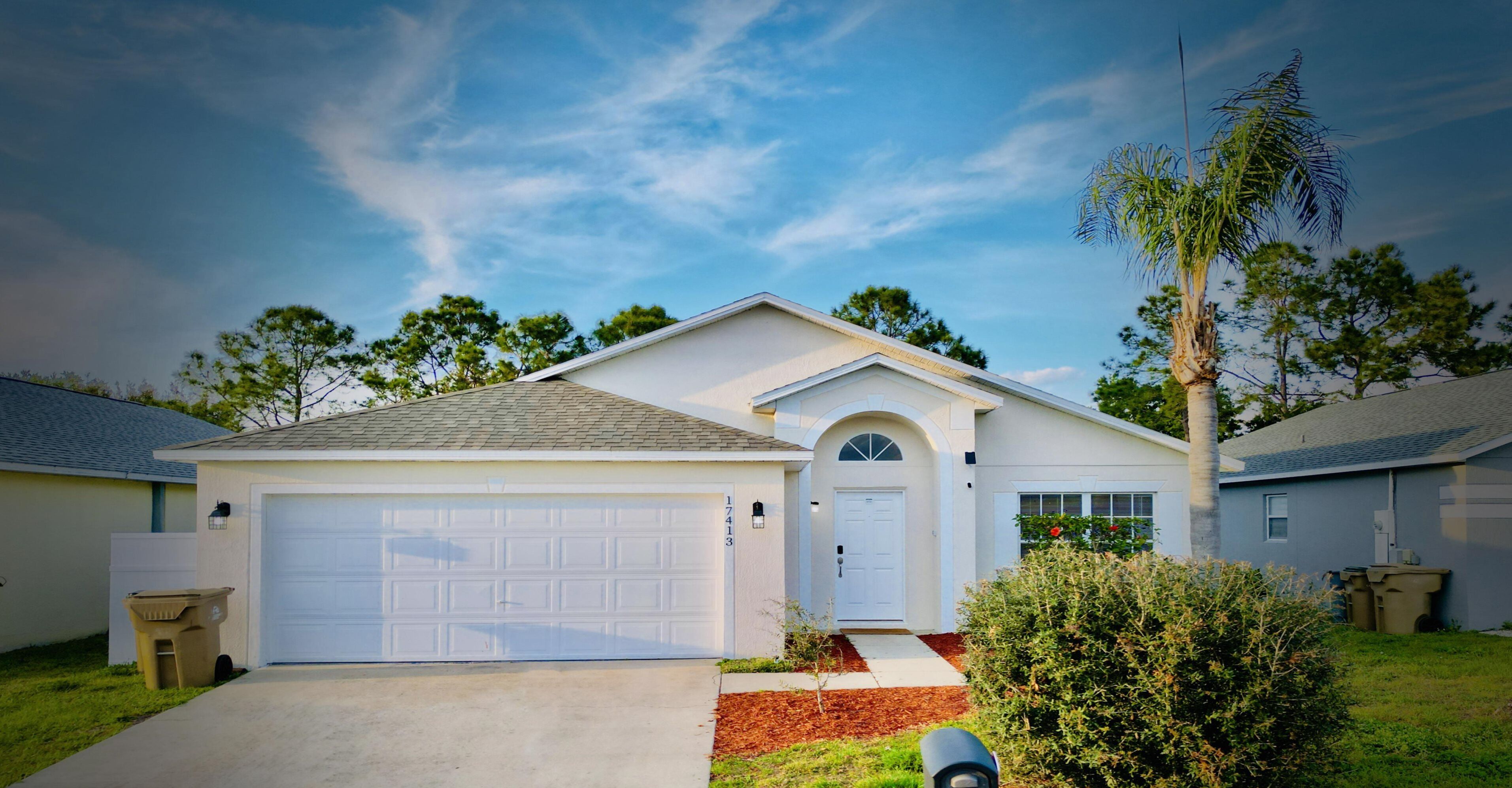 A single-story house with a white garage door, a front door with a small porch, and a mailbox.