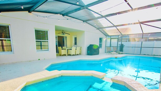 A swimming pool with a glass ceiling, a ceiling fan, and a patio area with chairs. - Fantastic 5BD House w/Private Pool - 9mi/Disney! (Clermont)