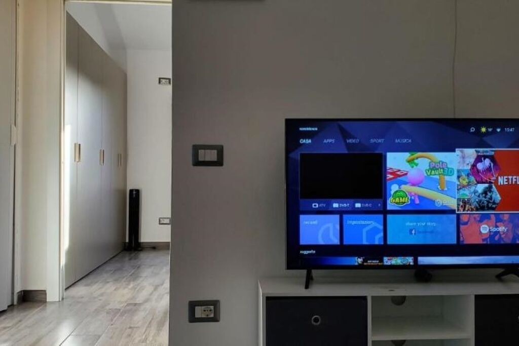 Un soggiorno moderno con una televisione a schermo piatto che mostra diversi servizi di streaming.