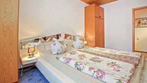 Une chambre à coucher comprenant un lit, des tables de chevet, une commode, une tête de lit en bois et une armoire.