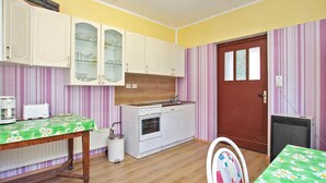 Une cuisine de taille réduite avec des meubles blancs, un plan de travail en bois et une porte rouge.