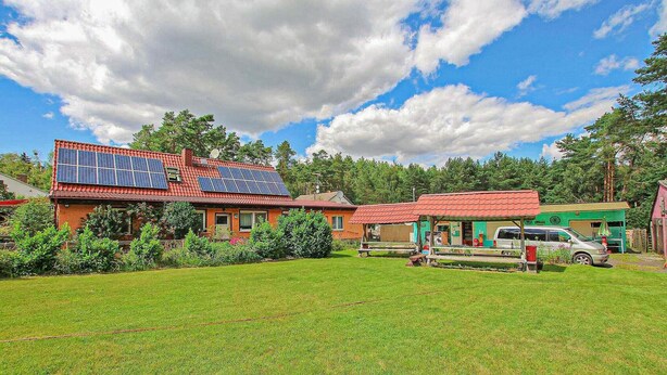 Une maison équipée de panneaux solaires, un bâtiment écologique, et une voiture garée dans la cour.