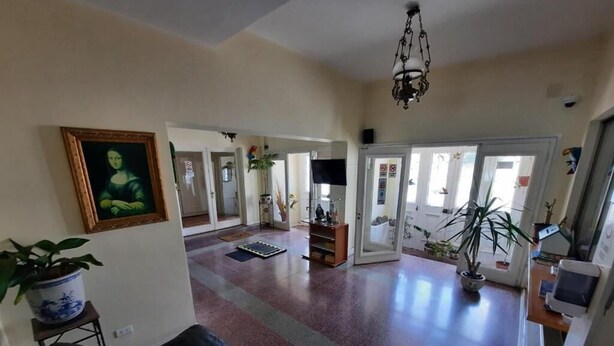 A spacious living area with a black leather sofa, a large painting on the wall, and a chandelier. - Residencial Metro Republica Santiago (Santiago)