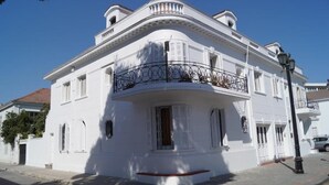 A white building with a curved facade, a balcony with wrought iron railing, and a street lamp. - Residencial Metro Republica Santiago (Santiago)