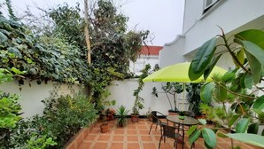 A patio with terracotta tiles, potted plants, and a table with chairs. - Residencial Metro Republica Santiago (Santiago)