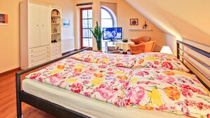 Een slaapkamer met een bed, een televisie, een bureau en een stoel.