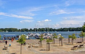 A marina with boats docked, a sandy beach with trees, and a clear sky. - Ferienwohnung Röbel/Müritz (Röbel/Müritz)