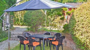An outdoor patio with a table and chairs, surrounded by greenery and a stone pathway. - Gorgeous apartment in Lychen with sauna (Lychen)
