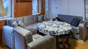A cozy living room with a round table covered with a patterned tablecloth, surrounded by cushioned seating. - Gorgeous apartment in Lychen with sauna (Lychen)
