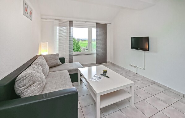 A modern living room with a sofa, a coffee table, and a TV mounted on the wall.
