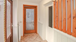 A hallway with a wooden door, a radiator, and a window with blinds. - Ferienhaus Lubmin (Seebad) (Lubmin (Seebad))