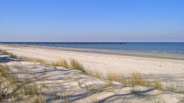 A beach with a long pier extending into the water, sandy dunes, and clear skies. - Ferienhaus Lubmin (Seebad) (Lubmin (Seebad))