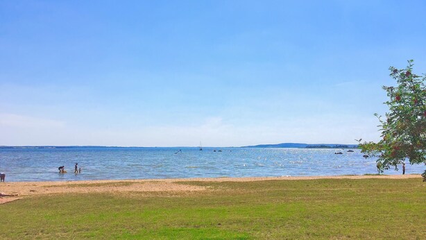 A beach with a clear sky, calm water, and a grassy area. - 3 bedroom stunning home in Verchen (Verchen)