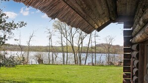 Eine Blockhütte mit Strohdach mit Blick auf einen See.
