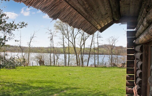 Una cabana de fusta amb teulada de palla amb vista a un llac.
