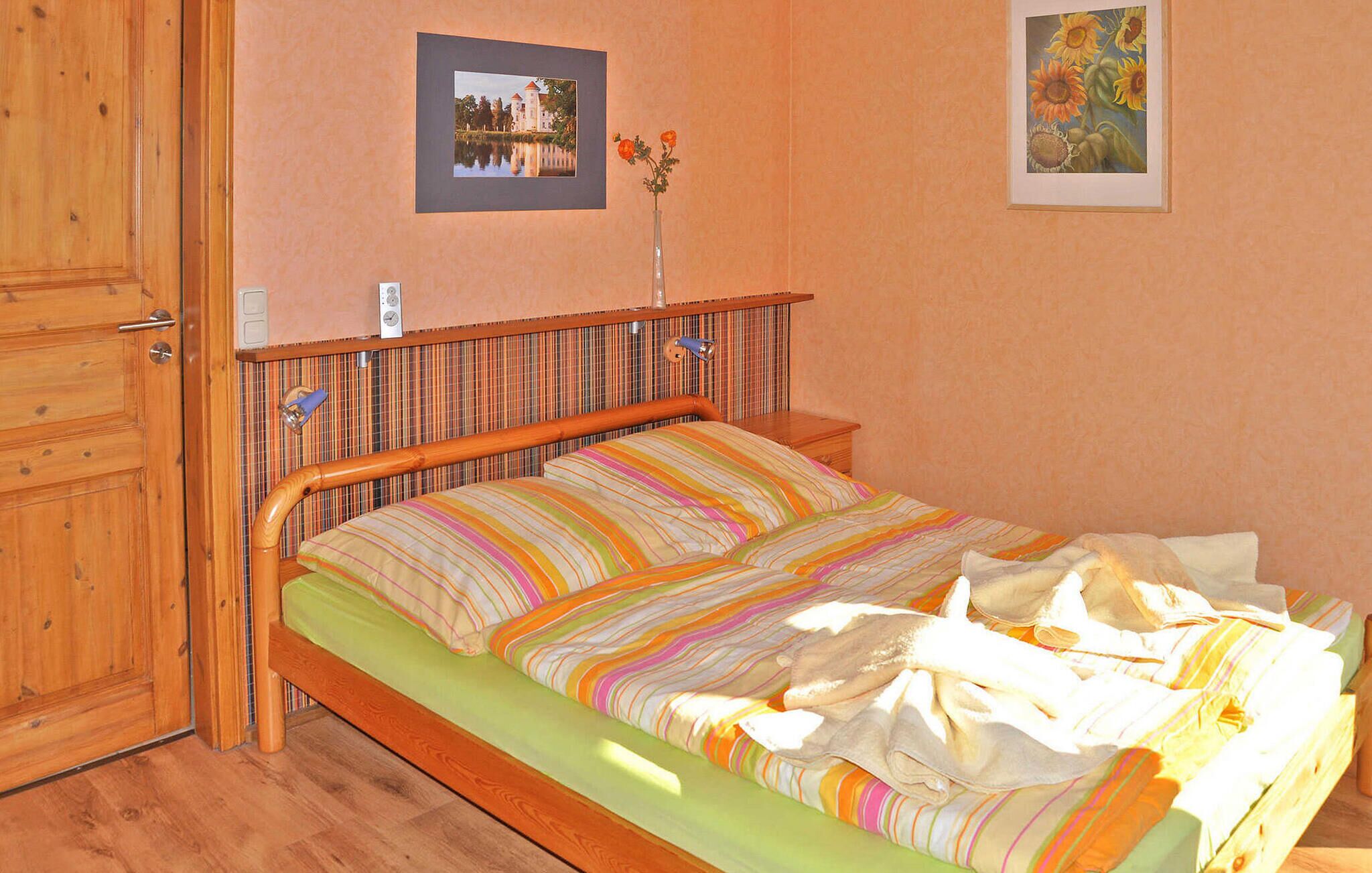Une chambre à coucher avec un lit en bois, une couvre-lit à rayures et deux tableaux encadrés accrochés au mur.