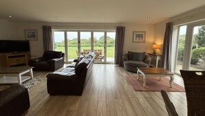 A spacious living room with a large sofa, a television, and a dining area with a table and chairs.