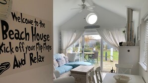 A beach house interior with a cozy seating area, a dining table, and a view of the backyard. - Sand Dollar (new for 2024) -  a beach house that sleeps 5 guests  in 2 bedrooms (Filey)