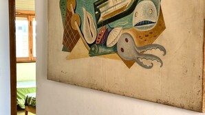 Pintura com peixes abstratos e um barco em uma parede.