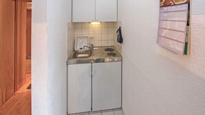 Un angolo cottura compatto con lavello, fornelli e pensili.