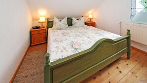 Una camera da letto con un letto di legno, biancheria da letto floreale, due comodini con lampade e un termosifone.