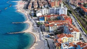 A coastal cityscape with a beach, colorful buildings, and a clear blue sea. - P024 - Porto Recanati, new three-room apartment facing the sea (Porto Recanati)