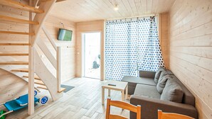 A wooden interior with a staircase, a sofa, a table, and a TV mounted on the wall. - Gorgeous home in Sarbinowo with WiFi (Sarbinowo)